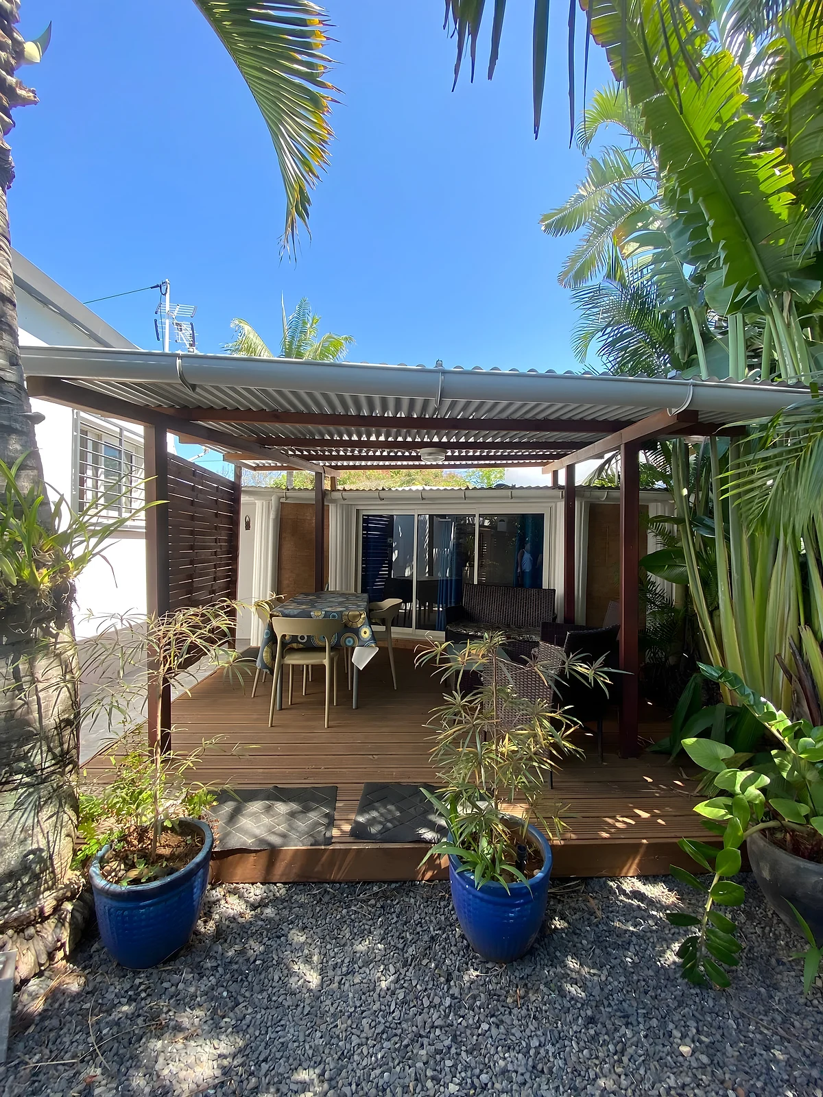 La terrasse du bungalow sous sa pergola, entourée de plantes en pots bleus