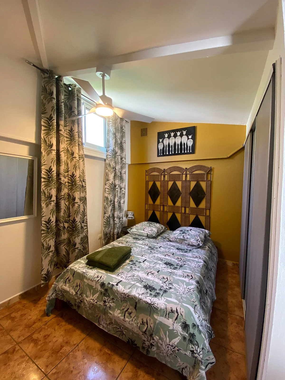 La chambre du bungalow, son lit et sa tête de lit en bois