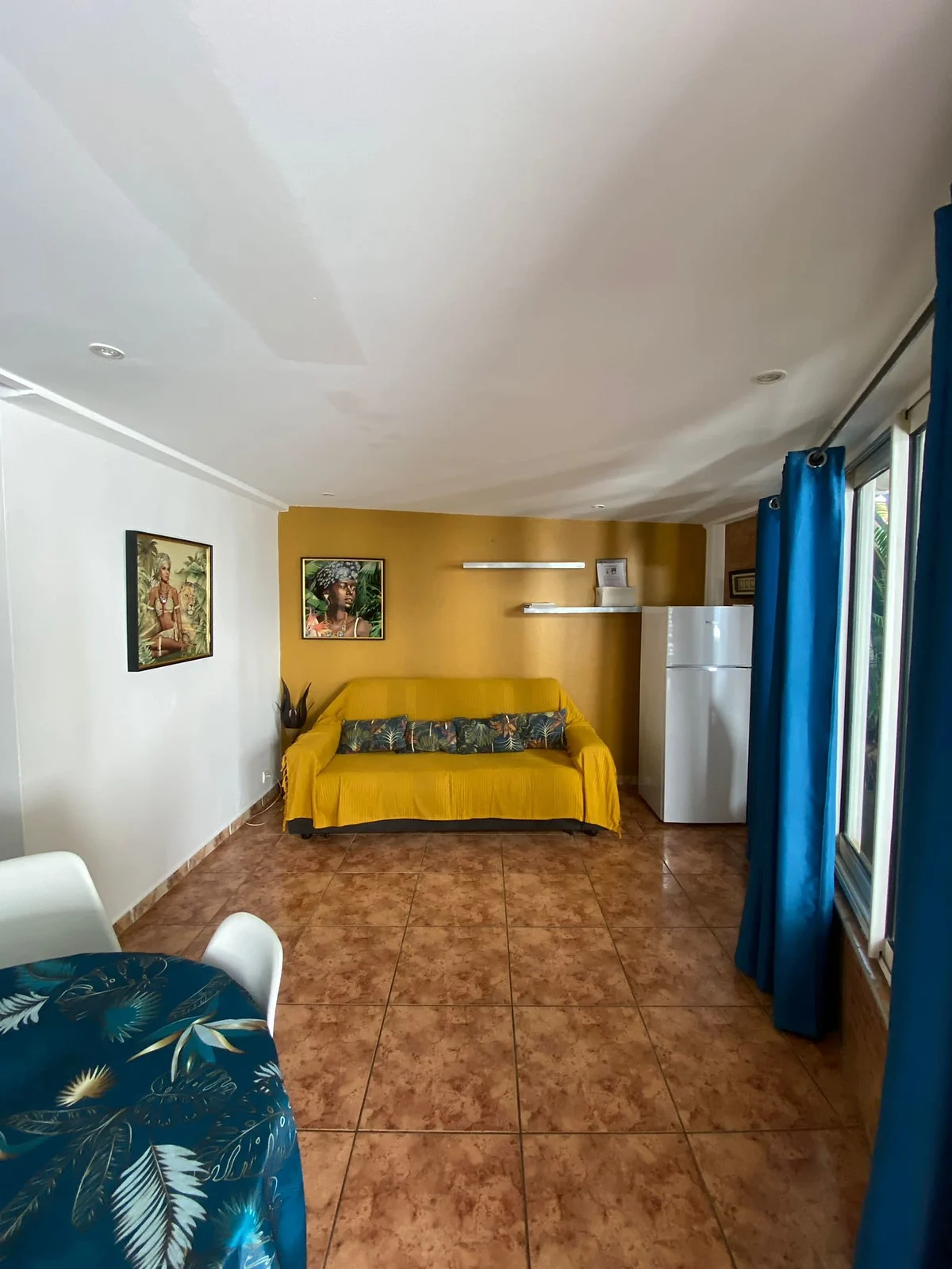 Le salon du bungalow, son canapé jaune et sa porte-fenêtre