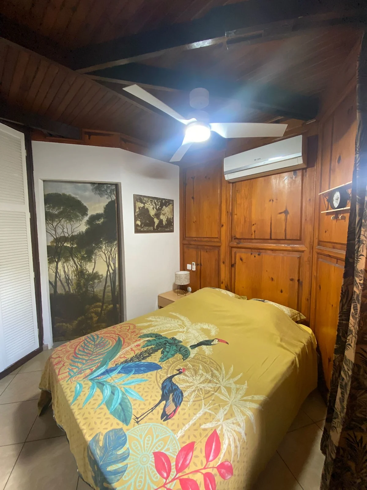 Une chambre du chalet, boiseries et couvre-lit jaune aux oiseaux
