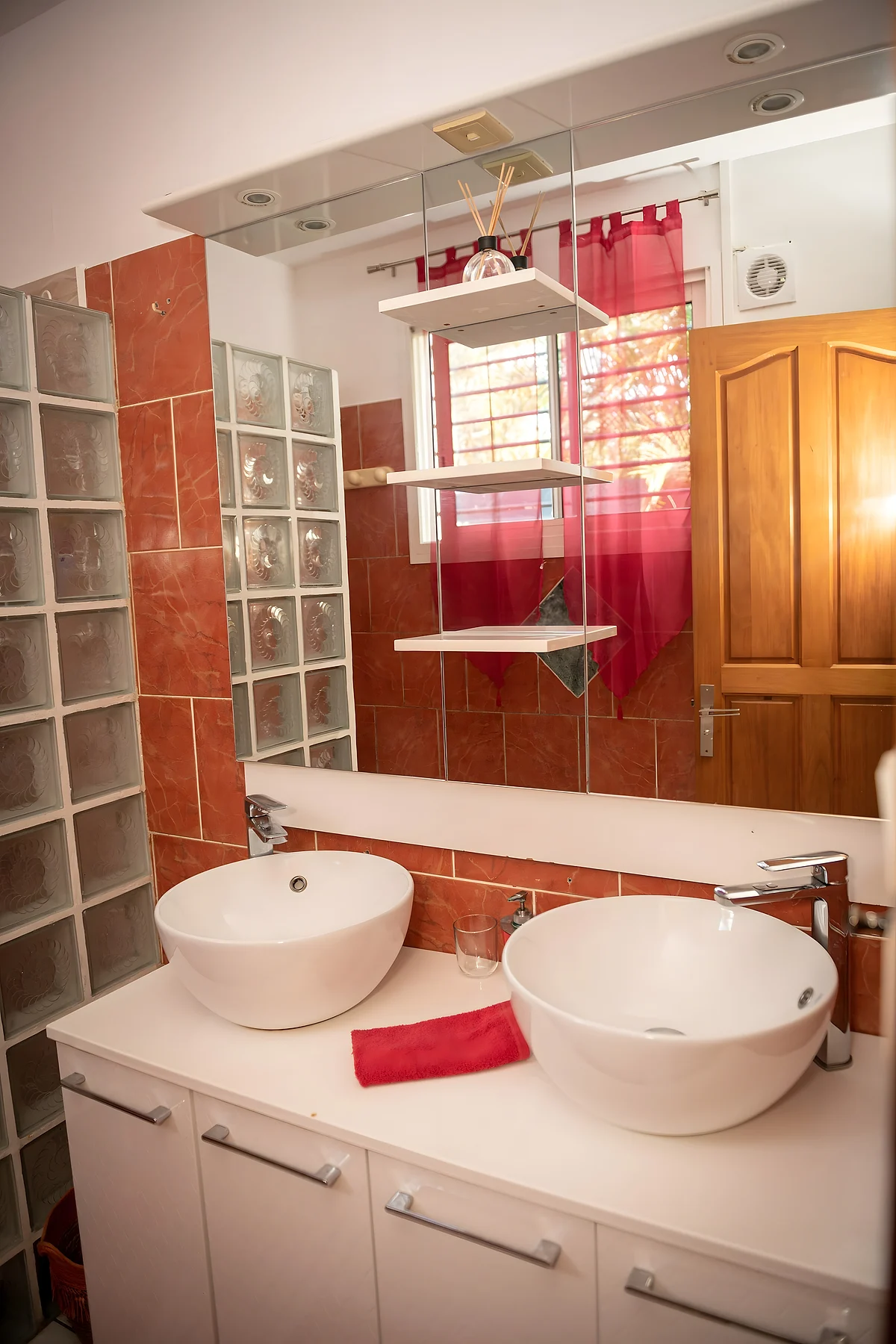 Les deux vasques de la salle de bain, sous la fenêtre aux rideaux rouges