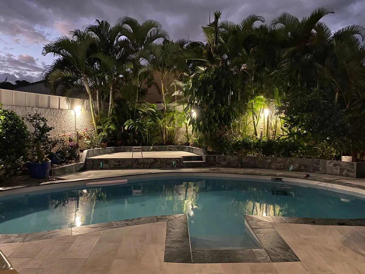 La piscine éclairée le soir, sous les palmiers