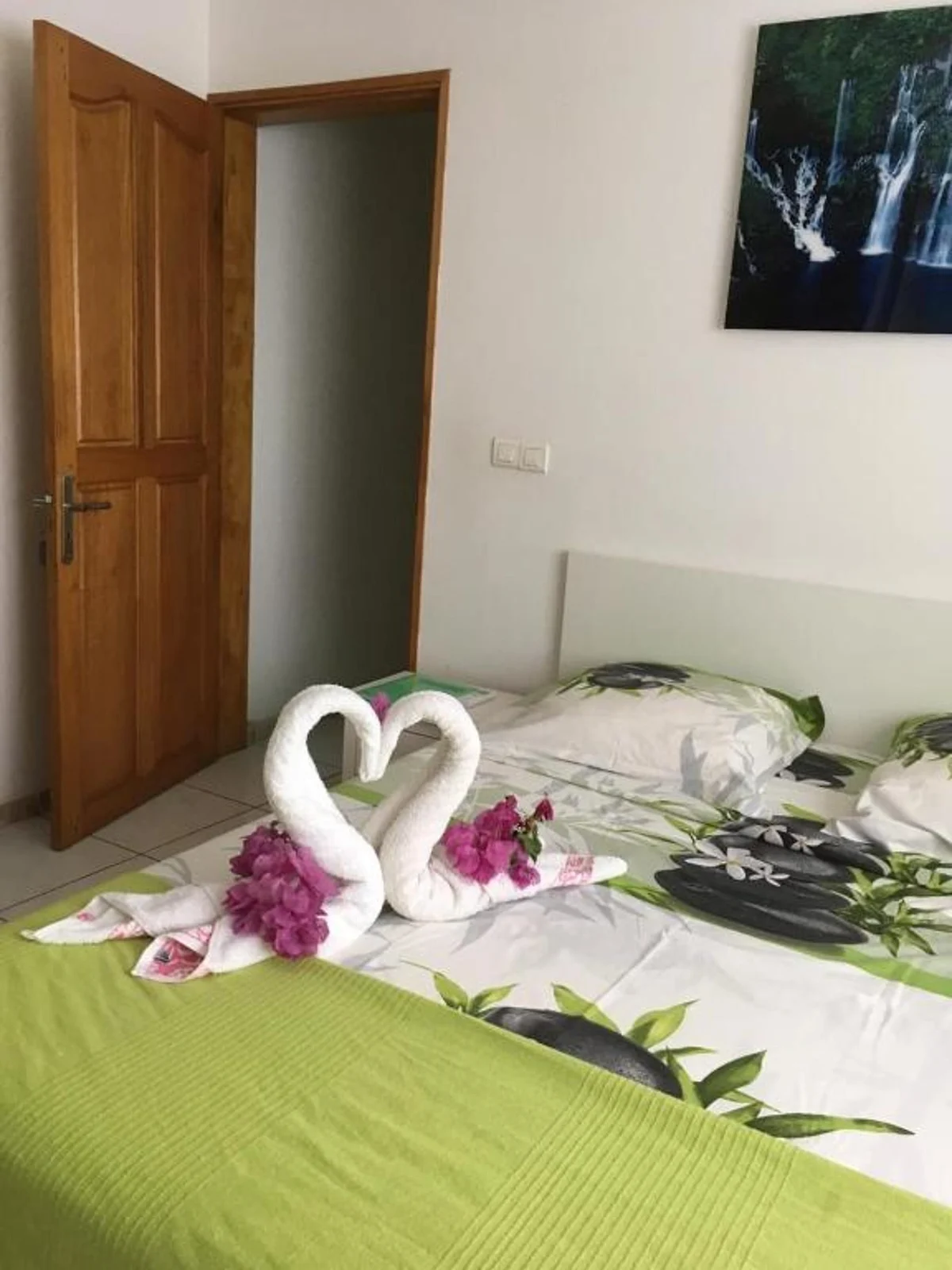 Deux cygnes en serviettes et des fleurs de bougainvillier posés sur le lit