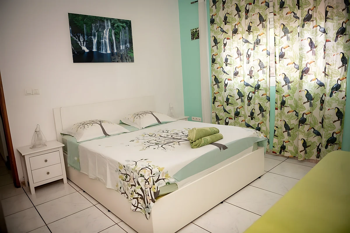 La chambre Toucan, son lit blanc et le mur vert d'eau