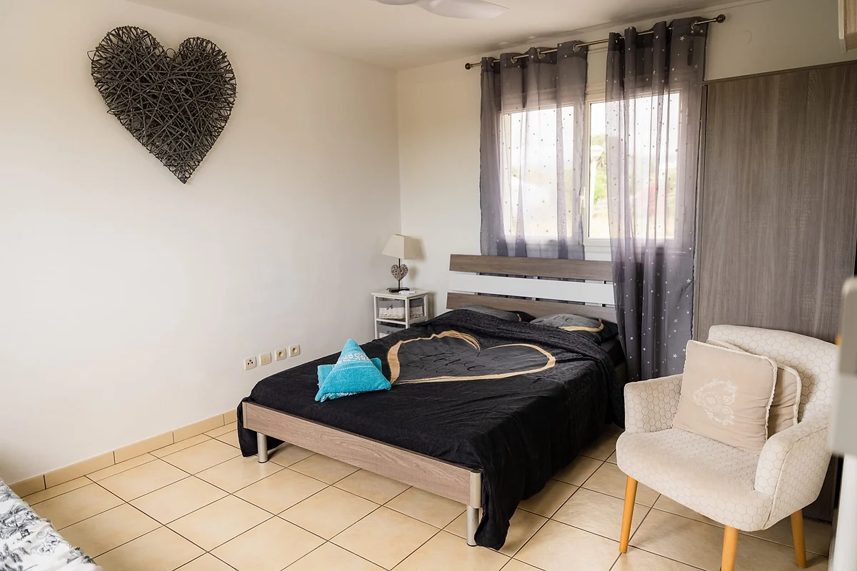 Une chambre de la villa, son grand lit et son fauteuil blanc