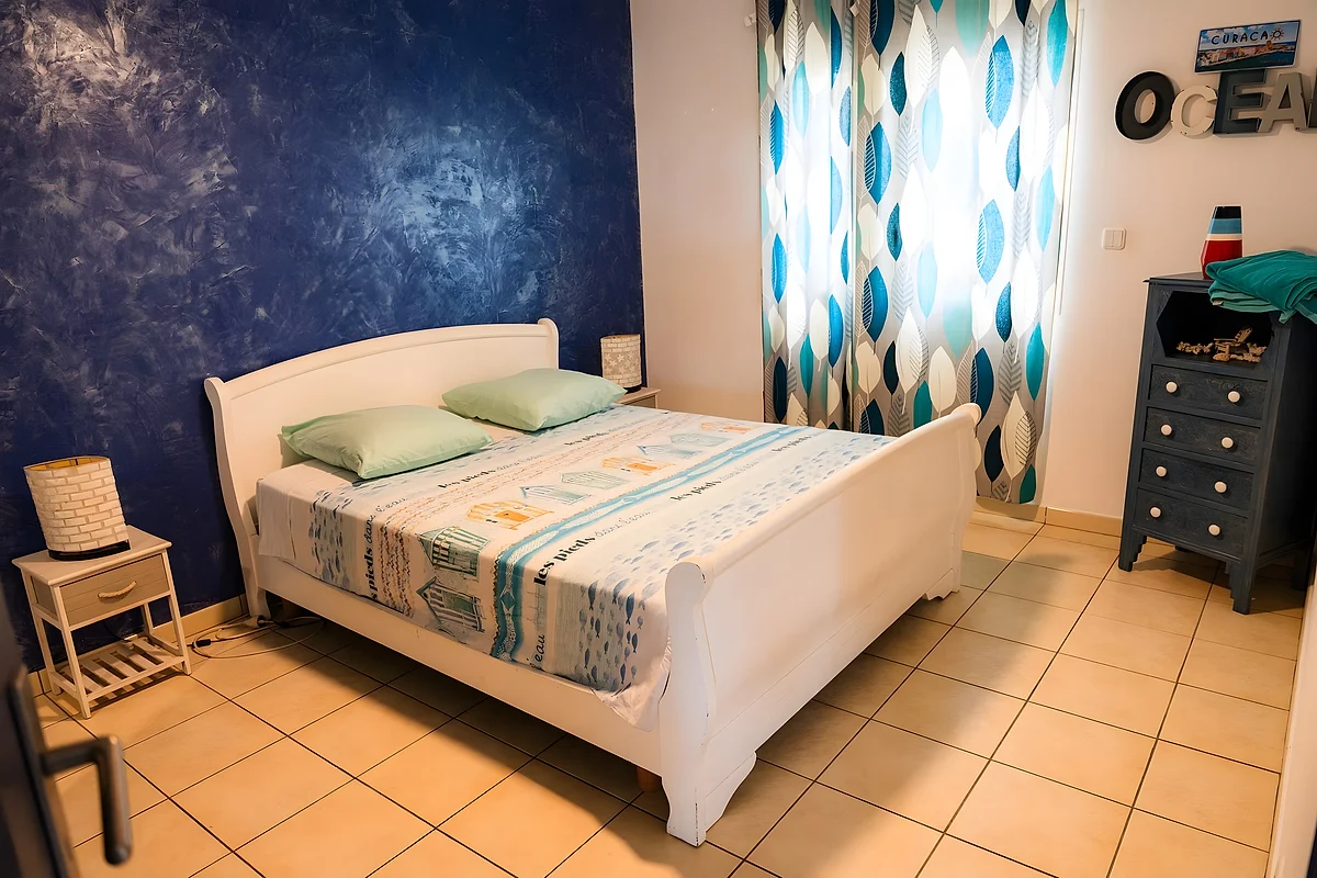 Une chambre de la villa, son mur bleu nuit et son lit blanc