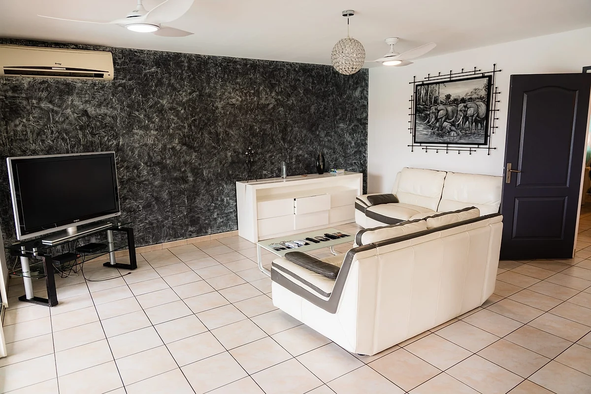 Le salon de la villa, son canapé blanc et sa télévision